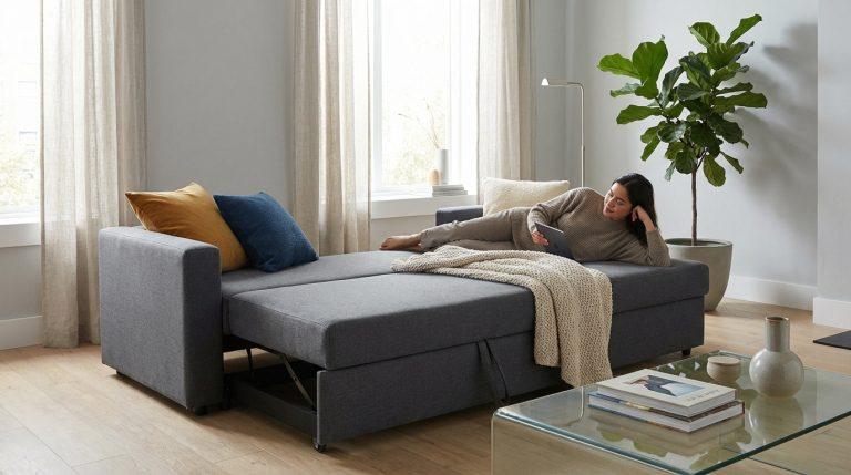 Canapé lit convertible Center : les meilleurs modèles et prix en 2026 Femme relaxant sur un canapé lit convertible gris anthracite, à moitié déployé, dans un salon lumineux.