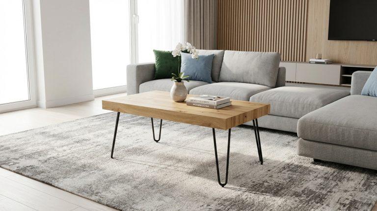 Salon moderne et chic avec une table basse rectangulaire en bois clair et pieds épingle noirs, devant un grand canapé gris.