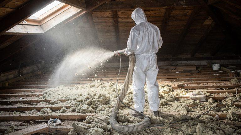 Isolation de 100 m² de combles perdus : combien ça coûte en 2026 ? Artisan soufflant de la laine de verre dans des combles perdus